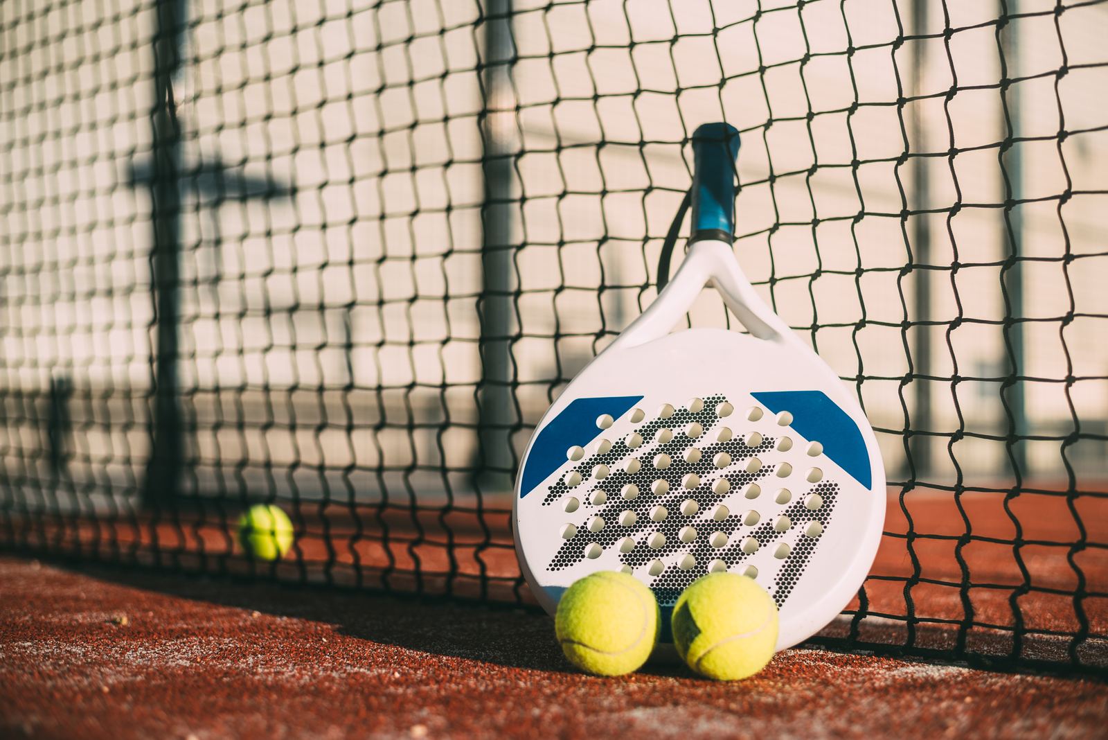 Padel racket resting on the net of a padel court